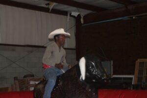 Jaylan Boudreax rides the mechanical bull at Rodeo Day at Trident Construction's May Superintendents Meeting.